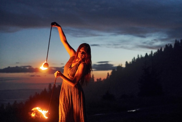 Show de fogo por mulher de vestido à noite Montanhas dos Cárpatos Bela paisagem