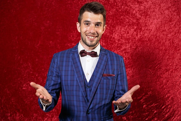 Showman alegre em elegante terno azul e gravata borboleta mostrando gesto de boas-vindas com as mãos