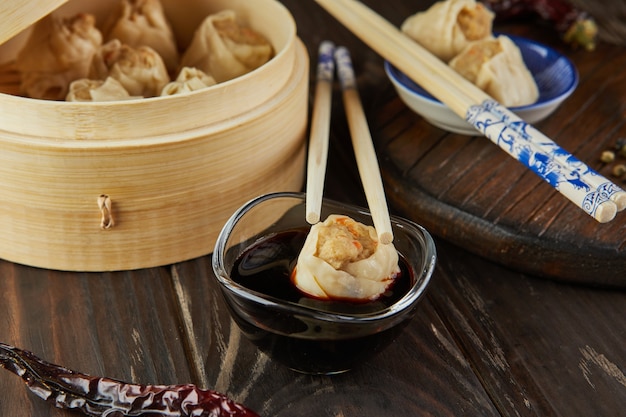 Shumai Shaomai Chinesischer Fleischknödel gedämpftes Gericht in Bambus-Dämpferbox. Essstäbchen und Dimsum.