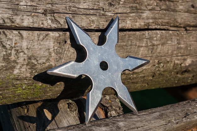 Shuriken estrella arrojadiza ninja japonés tradicional arma fría atascada en fondo de madera