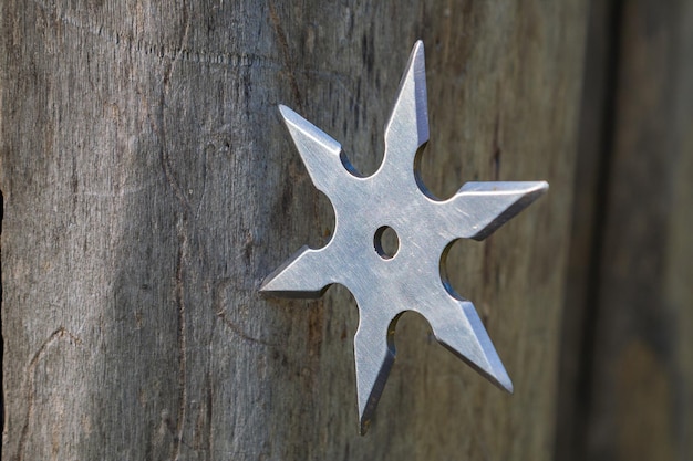 Shuriken estrella arrojadiza ninja japonés tradicional arma fría atascada en fondo de madera