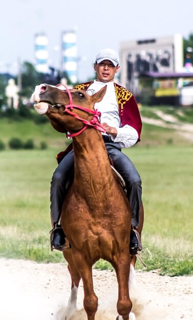 Shymkent Kazajstán 16 de mayo de 2018 Una fiesta en el hipódromo de la ciudad en honor al comienzo del mes sagrado de Ramadán jinetes en trajes nacionales a caballo