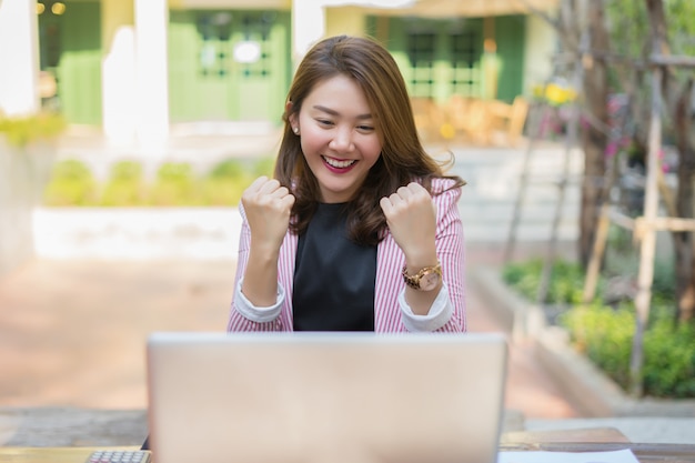 ¡Sí! Feliz mujer asiática emocionada en casa con las manos levantadas