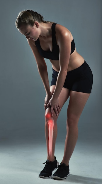 Si tus piernas se rinden, ve con tu corazón Foto de estudio de una joven deportista que sufre una lesión en la rodilla