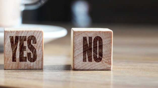 Sí versus no cubos de madera frente a la taza de cacao en la mesa Concepto de negocio