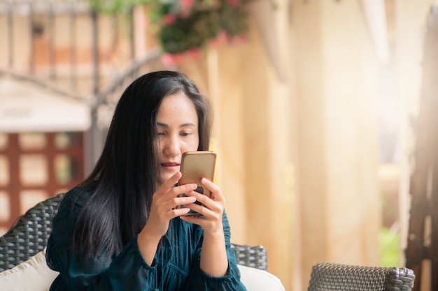 Ásia jovem mulher lendo a mensagem no smartphone na cafeteria