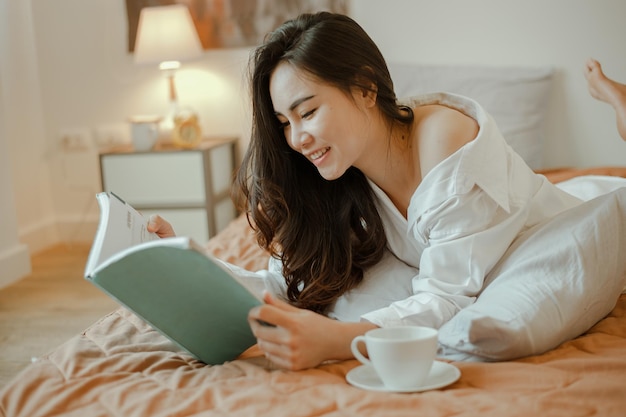 Ásia jovem vivendo em casa, relaxando e lendo um livro no quarto de férias. Asiático, ásia, relaxe, sozinho, tecnologia, conceito de estilo de vida.