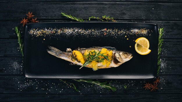 Sibas de pescado al horno con verduras y cítricos Sobre un fondo de madera negra Copiar espacio