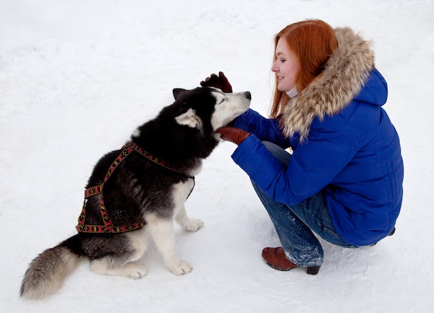 Sibirischer Husky der jungen Frau und des Hundes im Winter