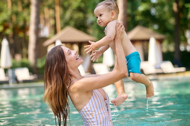 Sich ausruhen. Eine junge Frau, die ihr Kind hält und sich beim Schwimmen in einem Pool gut fühlt