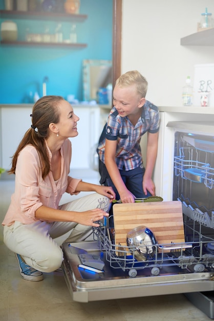 Sich gegenseitig zu helfen ist so eine Freude Aufnahme einer Mutter und ihres Sohnes, die eine Geschirrspülmaschine benutzen