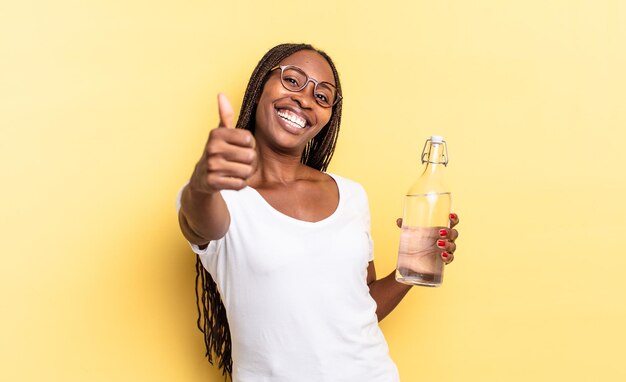 Sich stolz, unbeschwert, selbstbewusst und glücklich fühlen, positiv lächeln mit Daumen nach oben. Wasserflaschenkonzept