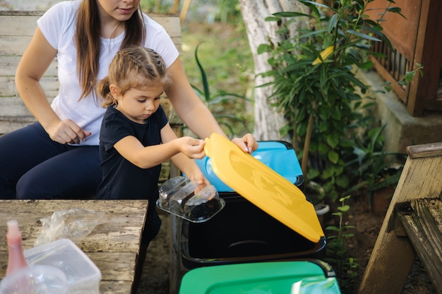 Sich um die Natur kümmern, junge Mutter mit ihrer kleinen Tochter, die sich auf das Recycling verschiedener Arten vorbereitet