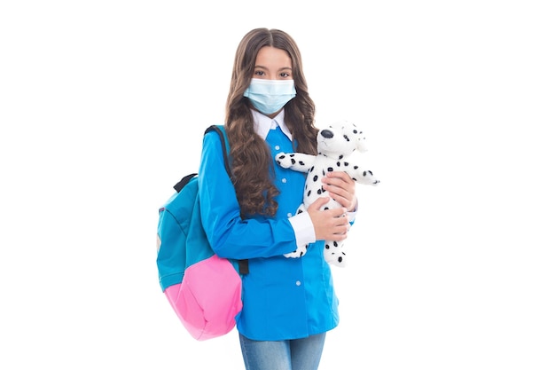 Sicher zu lernen während COVID-19. Kleines Kind trägt eine medizinische Maske, die einen Spielzeughund hält. Eine sichere Rückkehr in die Schule ist entscheidend. Sicherheit der Schüler. Bildung während der Pandemie. Verhinderung der Übertragung von SARS-CoV-2.