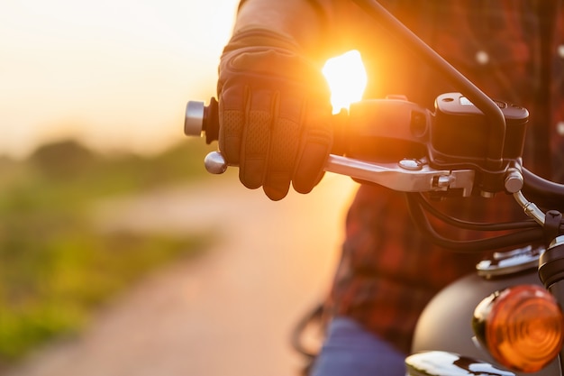 Sicheres Fahrkonzept. Makro rechte Hand des Motorradfahrers mit Reithandschuh auf der Handbremse. Außenaufnahmen auf der Straße mit Kopierraum