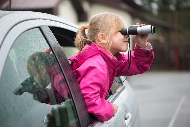 Foto sid sieht ein mädchen durch ein fernglas an, während es mit dem auto fährt