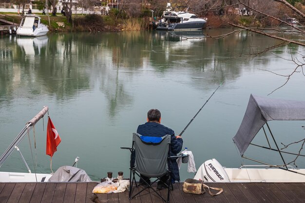 Side turkey 31 de janeiro de 2023 um pescador masculino com uma capa de chuva preta pega peixes no mar no inverno