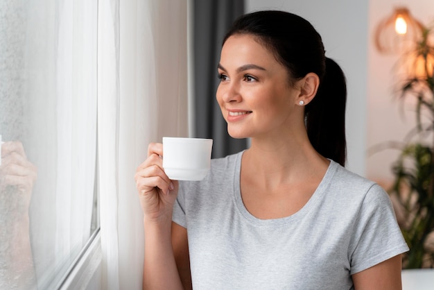 Sideview mujer embarazada sosteniendo su barriga mientras disfruta de una taza de té