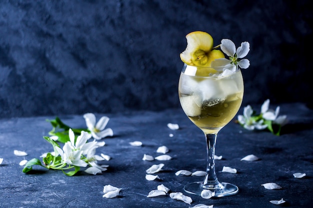 Sidra de maçã com cubos de gelo e flores em copo de vinho