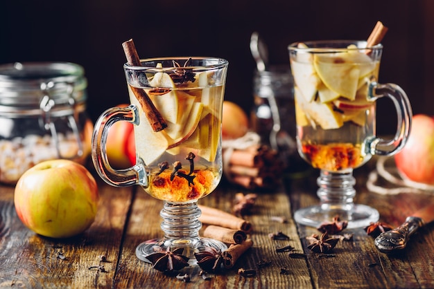 Sidra de manzana caliente e ingredientes en mesa de madera