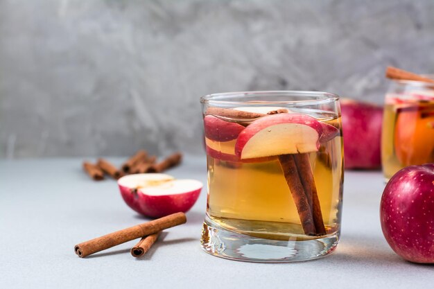 Sidra de manzana orgánica fresca con canela en vidrio y manzanas sobre un fondo gris. Bebidas calientes de invierno. Copia espacio