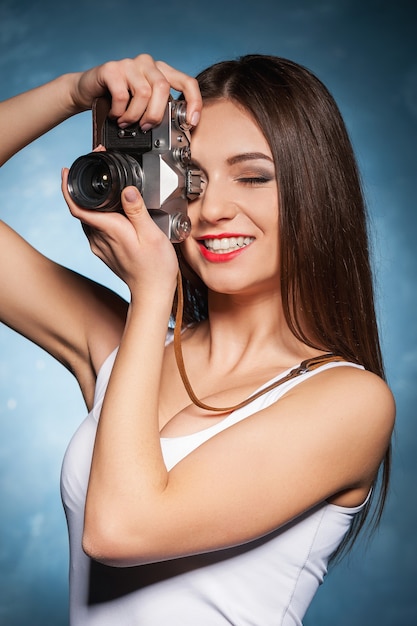 Sie fotografiert gerne. Schöne junge Frau, die sich mit Kamera fokussiert und lächelt