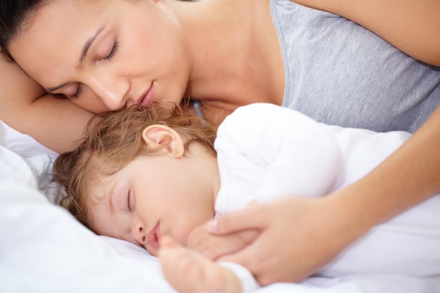 Sie ist genauso müde wie ihre Tochter Eine Mutter und Tochter, die auf dem Bett schlafen