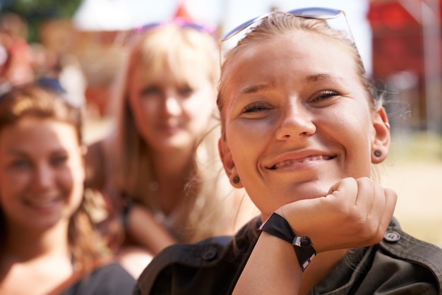 Sie ist zufrieden mit ihren Partypartnern. Porträt einer glücklichen jungen Frau, die mit dem Kinn lächelt, das auf ihrer Hand ruht, und Freunden, die im Hintergrund sitzen.