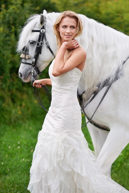 Sie kam zu Pferd zu ihrer Hochzeit Eine attraktive junge Braut draußen mit ihrem Pferd