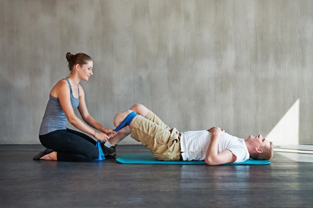 Sie schiebt ihn weiter. Einstellung einer Physiotherapeutin, die eine Sitzung mit einem jungen männlichen Amputierten hat