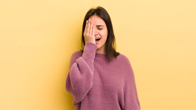 Sie sehen schläfrig gelangweilt aus und gähnen mit Kopfschmerzen und einer Hand, die das halbe Gesicht bedeckt