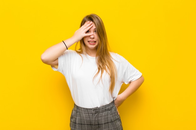 Sie sehen schockiert, verängstigt oder verängstigt aus, bedecken das Gesicht mit der Hand und spähen zwischen den Fingern