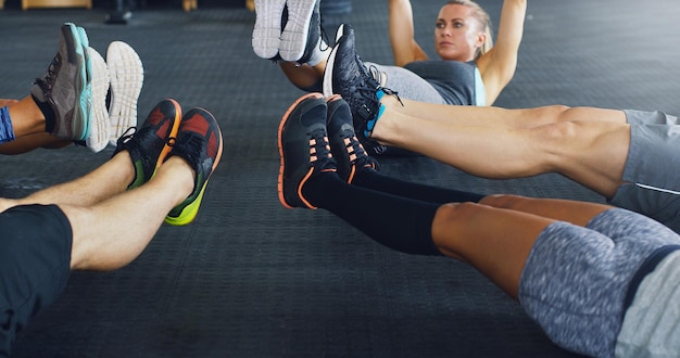 Sie setzen das Bein in den legendären Cropped Shot einer Gruppe von Menschen, die während ihres Trainings in einem Fitnessstudio im Kreis liegen