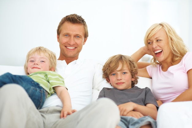 Sie sind eine junge und lebendige Familie Glückliche junge Familie, die zusammen zu Hause auf einem Sofa sitzt