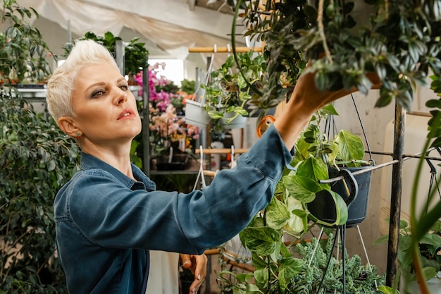 Sie untersucht Sämlinge Professionelle Floristin, die im Garten arbeitet