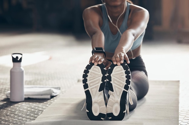 Sie werden sich anstrengen, wenn Sie sich nicht dehnen. Nahaufnahme einer nicht erkennbaren Frau, die sich beim Training in einem Fitnessstudio die Beine streckt.