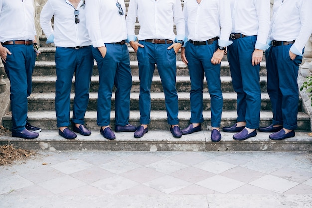 Sieben beste Männer des Bräutigams in identischen blauen Hosen und Schuhen stehen auf der Treppe, Nahaufnahme