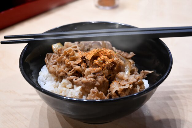 Sieden Sie Scheibenrindfleisch mit Reis in der japanischen Art.