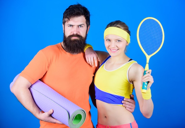 Sieg und Erfolg Sportliches Paartraining mit Fitnessmatte und Tennisschläger Glückliche Frau und bärtiger Mann trainieren im Fitnessstudio Sportgeräte Starke Muskeln und Körper bereit für den sportlichen Erfolg des Sieges