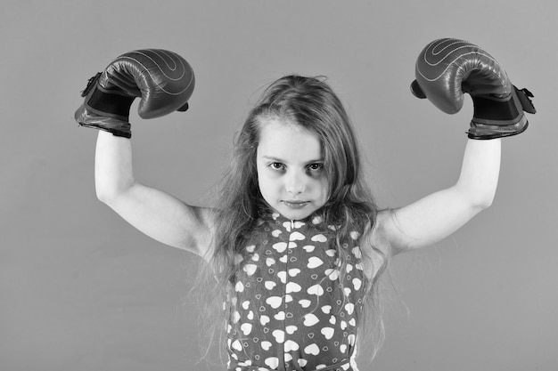 Siegermeister Sieger Kind flexiert Arme mit Muskelbiceps Triceps in Boxhandschuhen Kind Boxer mit langen Haaren auf rotem Hintergrund Mädchen Power Feminismus Konzept Sport Energieaktivität