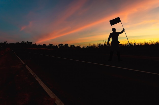 Siegkonzept, eine Silhouette eines Mannes, der am Sonnenuntergangshimmel steht.