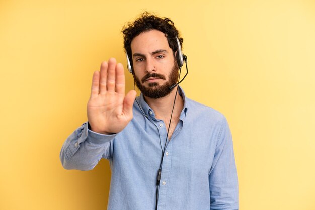 Sieht ernst aus und zeigt eine offene Handfläche, die eine Stopp-Geste macht