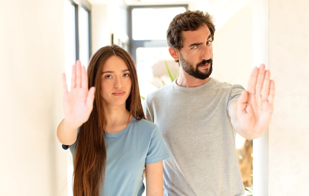 Sieht ernst, streng, unzufrieden und wütend aus und zeigt eine offene Handfläche, die eine Stopp-Geste macht