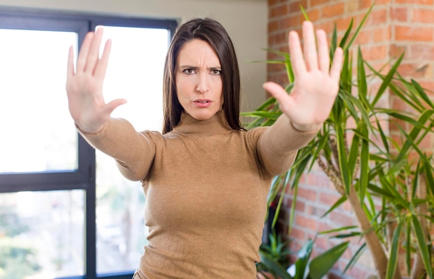 Foto sieht ernsthaft unglücklich, wütend und unzufrieden aus, verbietet den eintritt oder sagt stopp mit beiden offenen handflächen