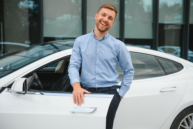 Siempre disponible Apuesto joven empresario cerca de su coche al aire libre