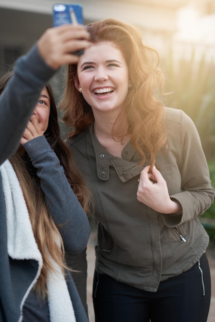 Siempre hay tiempo para una selfie Fotografía de dos mujeres jóvenes tomándose una selfie al aire libre