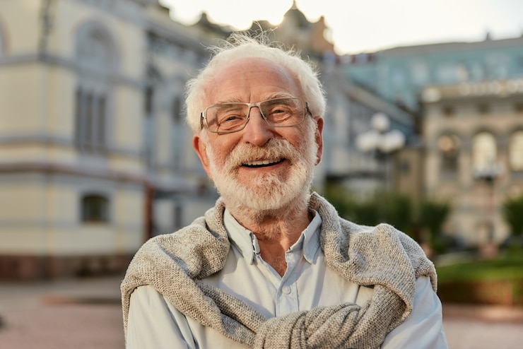 Foto siempre joven retrato de hombre mayor barbudo guapo con gafas mirando a cámara y sonriendo