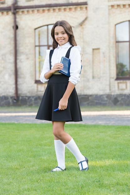 Foto siempre lleno de inspiración niña feliz de regreso a la escuela adorable niño pequeño con cabello largo y moreno en ropa formal sonrisa de niño pequeño en la escuela niño lindo va a la lección de literatura