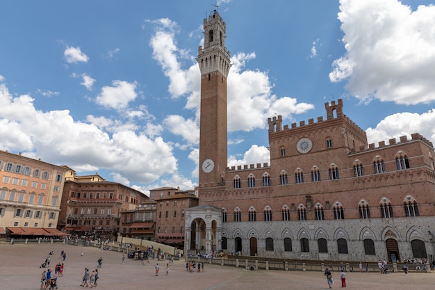 Siena, Italia - 28 de junio de 2018: Vista panorámica del Palazzo Pubblico (ayuntamiento) es un palacio y Torre del Mangia es una torre en la ciudad de Piazza del Campo. Día soleado de verano y espectacular cielo azul