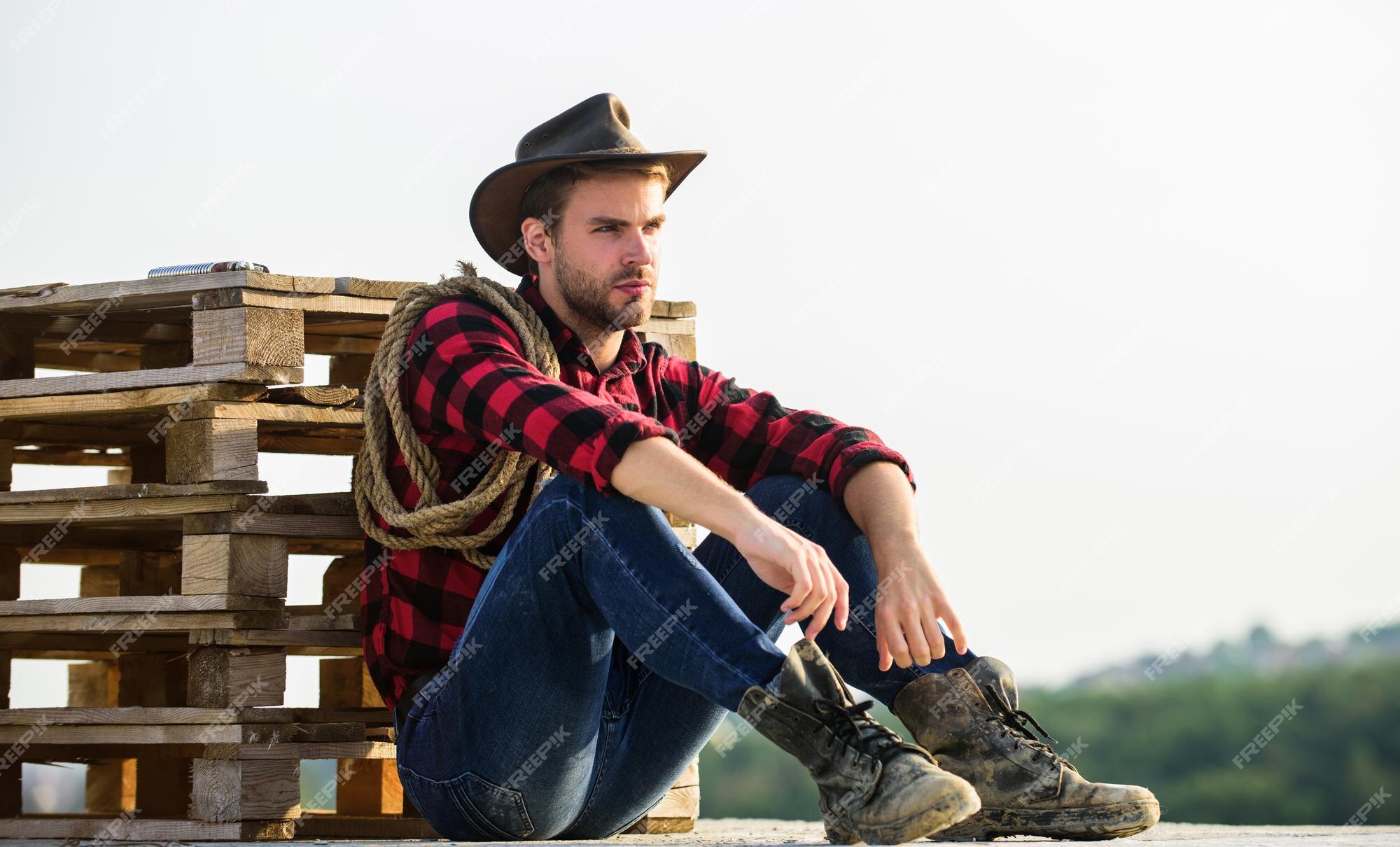 Siendo un hombre de estilo vintage salvaje oeste vaquero retro vaquero con cuerda de lazo rodeo del hombre pensativo con sombrero relajarse vaquero occidental retrato hombre camisa a